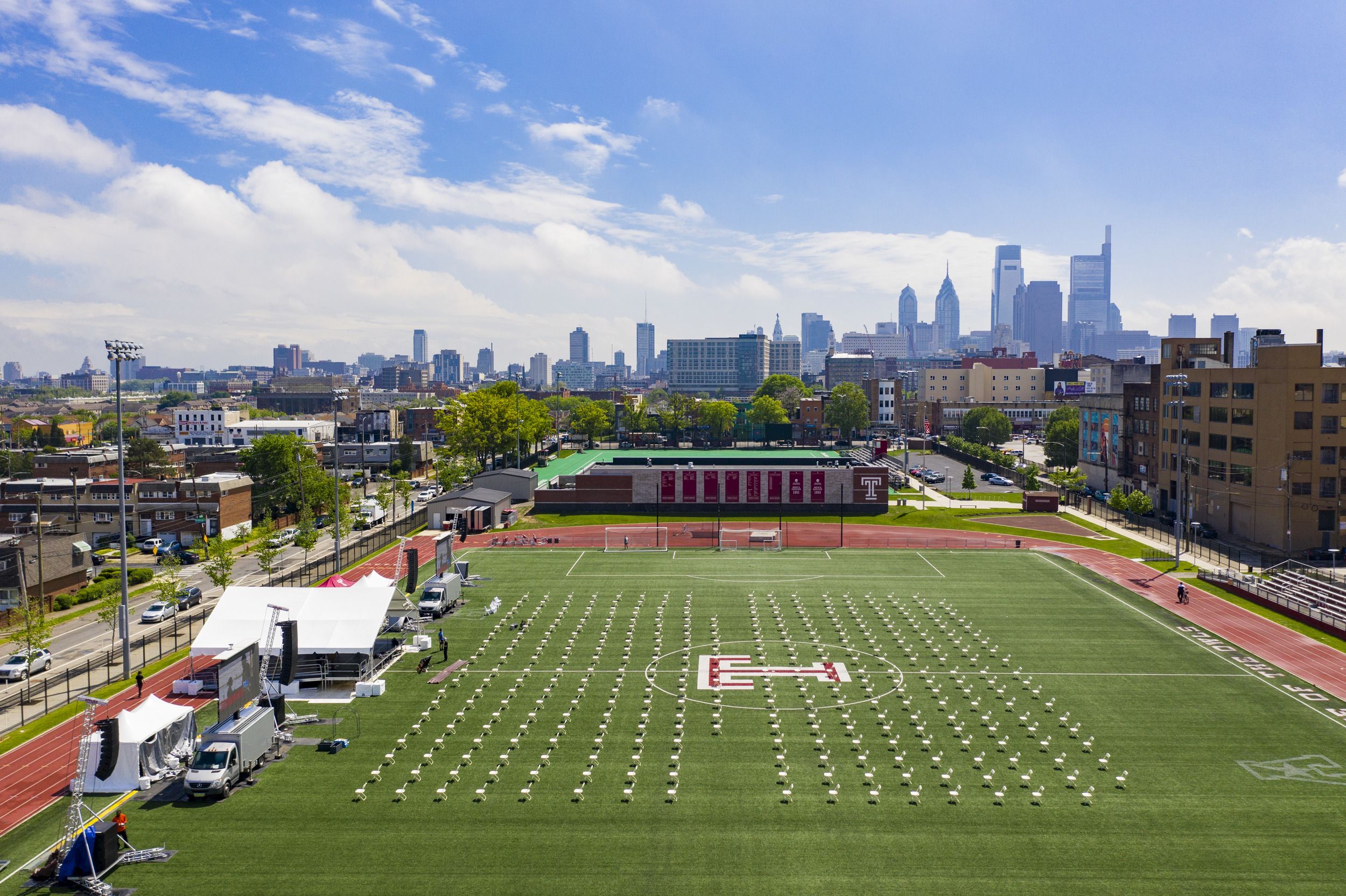 The Temple Sports Complex with the Philadelphia skyline in the background and empty chairs on the green in preparation for Commencement. 