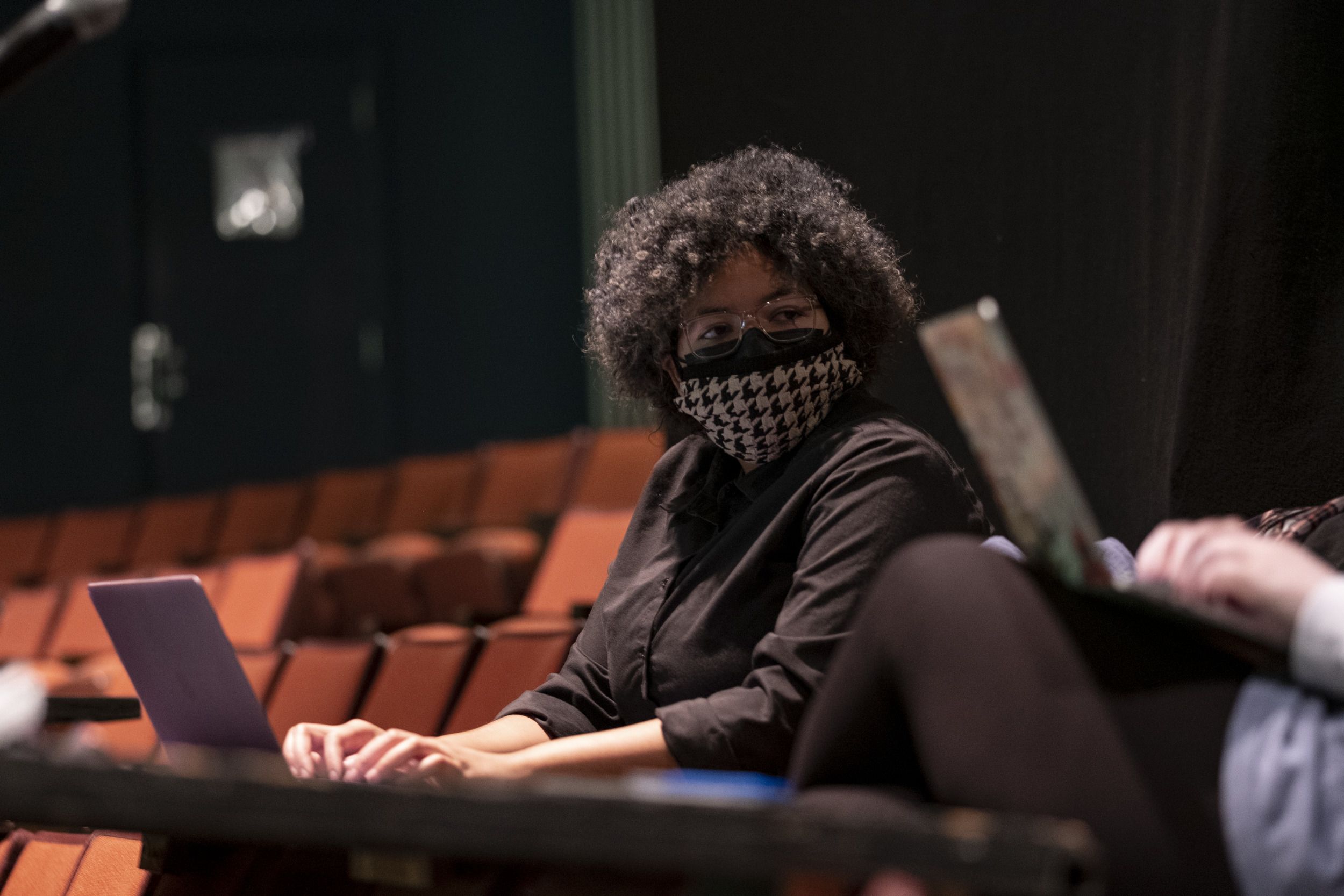 A crew member sitting, and typing on a laptop.